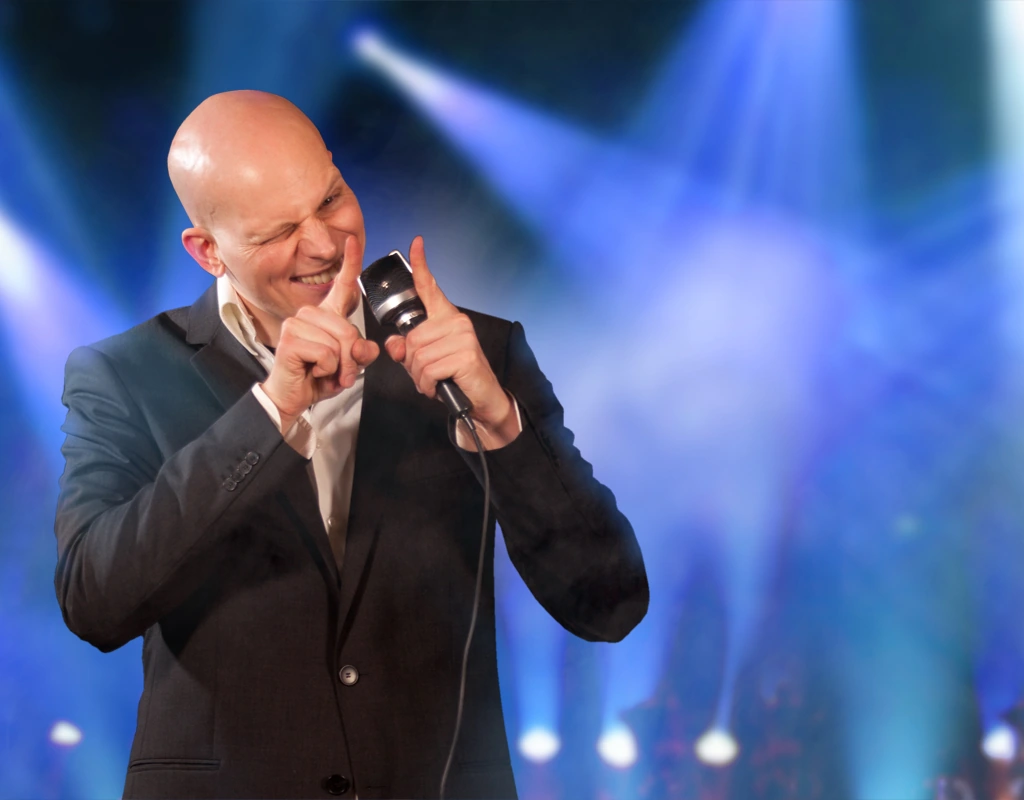 Florian Severin hosting with a microphone in front of blue stage lights