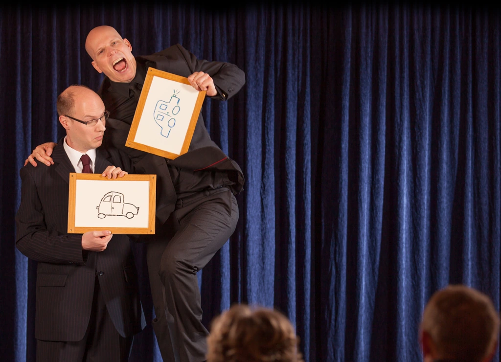 Florian Severin on stage with a spectator, both holding picture frames